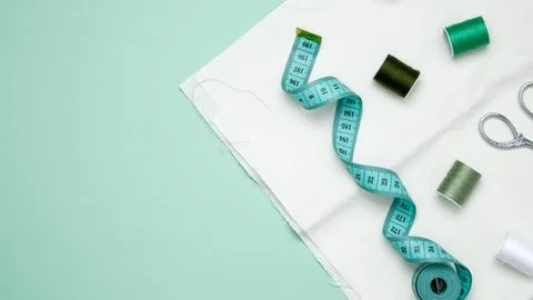 Composition with various threads and sewing accessories on green background.  Stock Photos