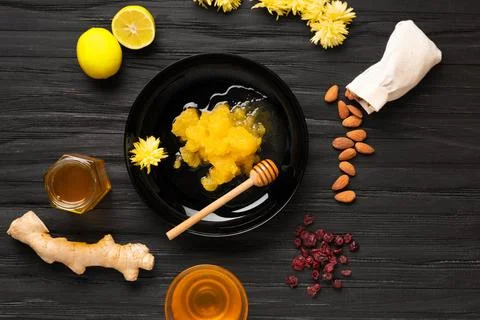 Composition of various types of honey, ginger, almonds, lemon on a dark woo.. Stock Photos