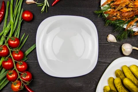 Composition with white plate and crayfish, rosemary, pepper, garlic, tomatoes Stock Photos