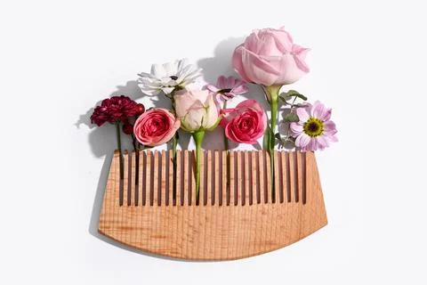 Composition with wooden comb and different flowers on white background Foto stock
