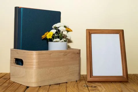 Composition on wooden table: box with books, vase of flowers and photo frame  Stock Photos