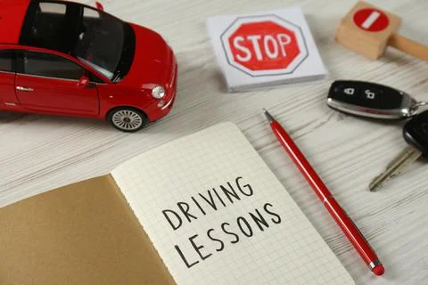 Composition with workbook for driving lessons and toy car on white wooden bac Stock Photos
