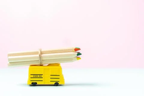 Composition with yellow school bus model and wooden colour pencils on pink ba Stock Photos