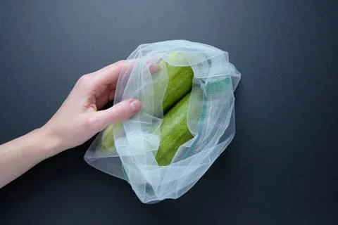 Composition with zucchini in a string bag on a black background. Zero waste. Stock Photos