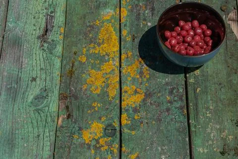 Compote cherries in a deep bowl, which stands on greenish old mossy boards .. Stock Photos
