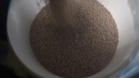 Compound feed for quails is being poured into a white bucket, close-up Stock Footage 322104937