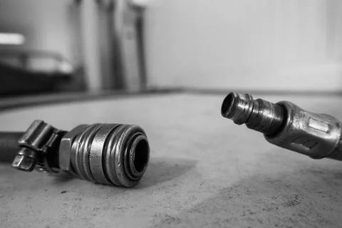 A compressed air hose with coupling is lying on the floor of a workshop Stock Photos