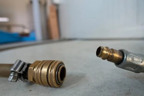 A compressed air hose with coupling is lying on the floor of a workshop Stock Photos