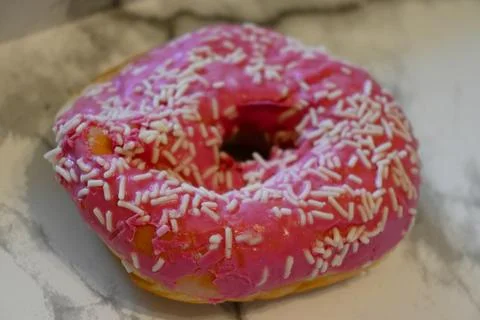 Compressed donut with pink icing and sprinkles Foto stock