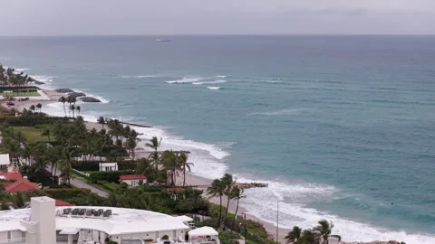 Compressed drone shot parallaxing along Palm Beach oceanfront with waves Stock Footage 334810242