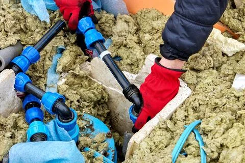 Compression fitting in hand of plumber repairing well pit. Stock Photos