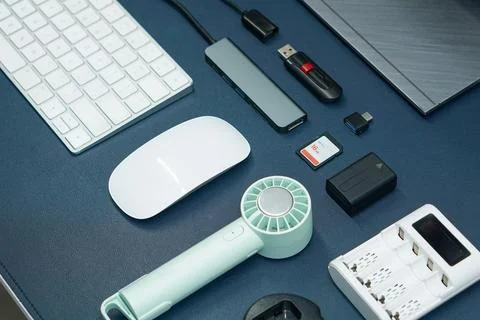 Computer accessories and digital gadgets arranged on a dark blue desk surface Stock Photos
