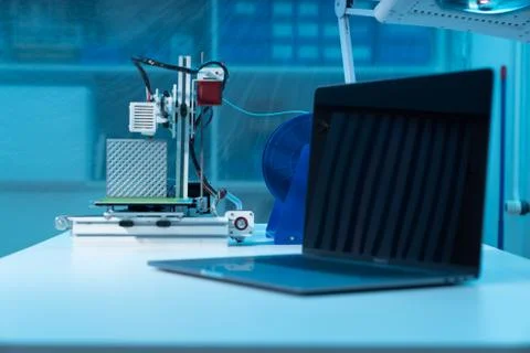 Computer and 3d printer on table in industrial design lab Stock Photos