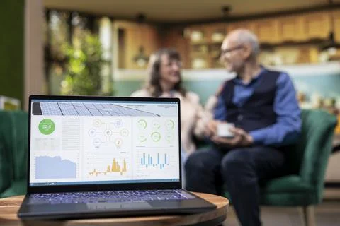 Computer app managing clean renewable energy at home for elderly couple 库存照片