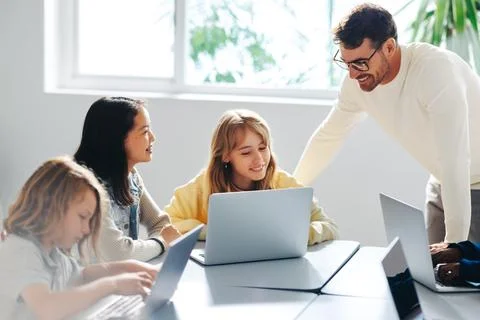Computer-based learning in an elementary school: Teacher guiding a group of.. 库存照片
