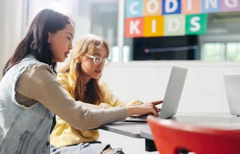 Computer-based learning for kids: Two girls assisting each other as they le.. 库存照片