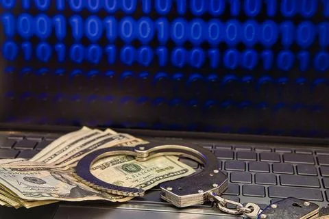 Computer with binary data on the screen, handcuffs and money on the keyboard Stock Photos