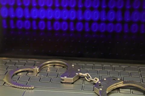 Computer with binary data on the screen, handcuffs on the keyboard 写真素材