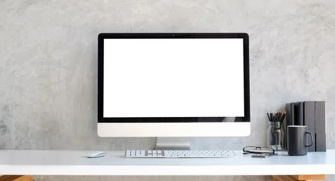 Computer with blank white display and supplies on white table.. Stock Photos