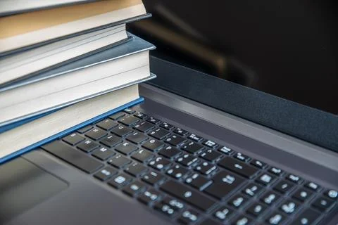 Computer, with books placed on the keyboard. E-learning.  Stock Photos