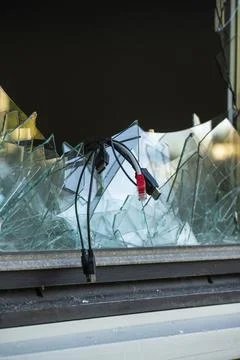 Computer cables hanging out of a broken window after a break in and theft Stock Photos