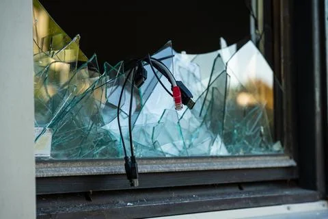 Computer cables hanging out of a broken window after a break in and theft. Stock Photos
