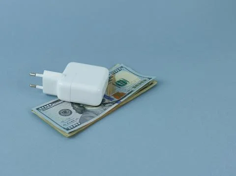 A computer charger on a bundle of dollars. Stock Photos