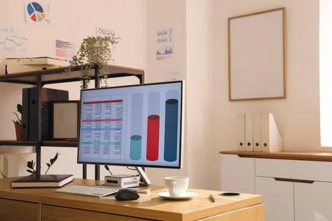 Computer with chart on desk in data scientist's office 库存照片