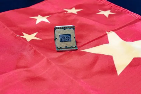 A computer chip rests on a Chinese flag, illustrating technological progres.. Stock Photos