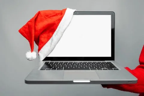 Computer in a Christmas hat, with a blank screen, on a gray background. Stock-Fotos
