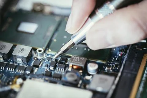 Computer circuit board, hand and screwdriver: Technician is fixing a motherboard Stock Photos