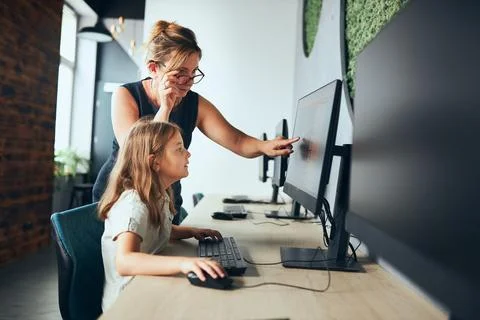 Computer class at school. Teacher assisting schoolgirl while class at prima.. Stock Photos