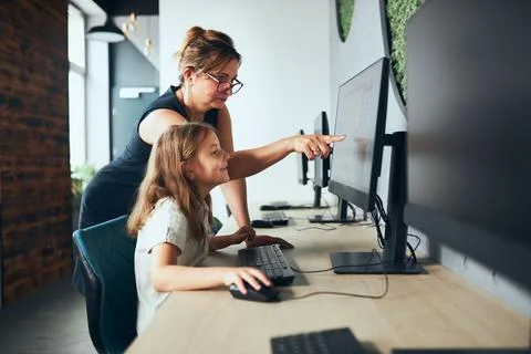 Computer class at school. Teacher assisting schoolgirl while class at prima.. 库存照片