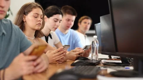 At computer class, young girl student sits with mobile phone and listens Stock Footage 307147213
