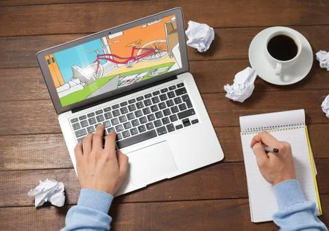Computer coffe, notebook and hands on a desk. In the computer the blueprint of Stock Photos