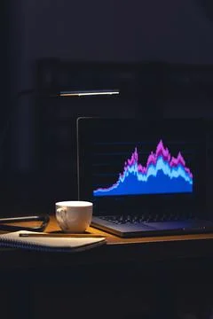 Computer in a dark room with graphs on the screen. Stock Photos