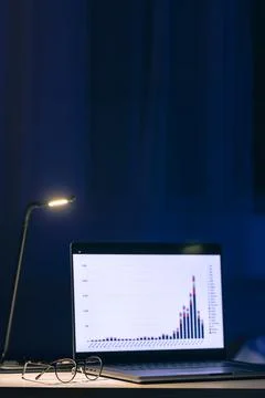 Computer in a dark room with graphs on the screen. Stock Photos