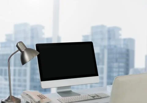 Computer on desk against city window Stock Photos
