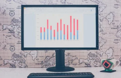 Computer desktop with graphs, keyboard and coffee mug on white table in sunny Stock Photos