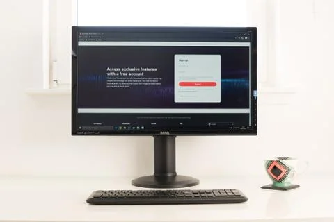 Computer desktop with Shutterstock website on screen. Keyboard and coffee mug Stock Photos