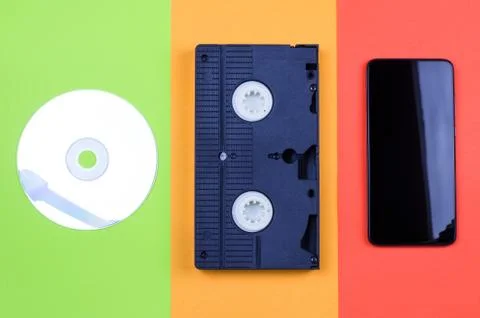 Computer disk, videotape and smartphone on a multicolored background. Stock Photos