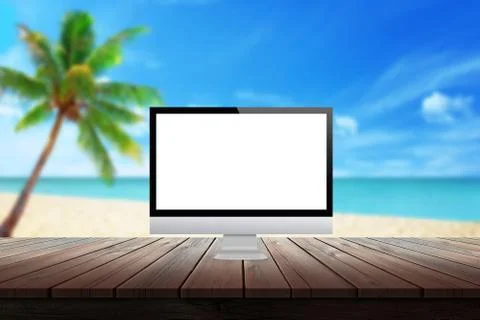 Computer display on desk with beach palm tree and sea in the background. Stock Photos