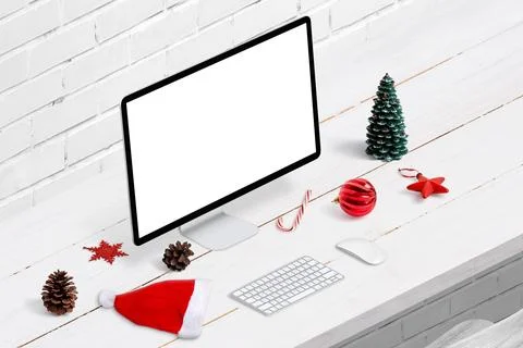 Computer display mockup on work desk surrounded by Christmas decorations. Iso Stock Photos