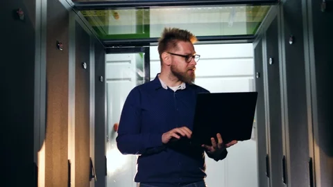 Computer engineer walks in data center, checking computers. Stock Footage 118616349
