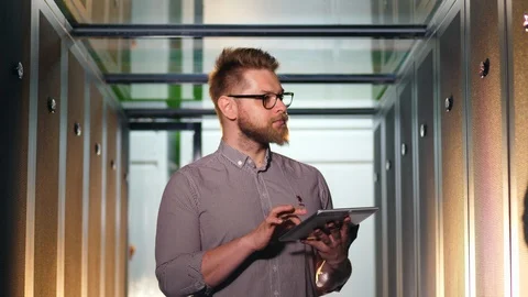 Computer engineer works with tablet while checking computers at data center. Video stock 118614733
