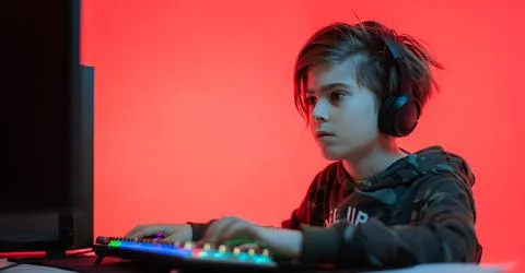 Computer games, playing place, young gamer plays computer games with headphones, Foto stock