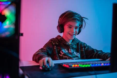 Computer games, playing place, young gamer plays computer games with headphones, Stock Photos