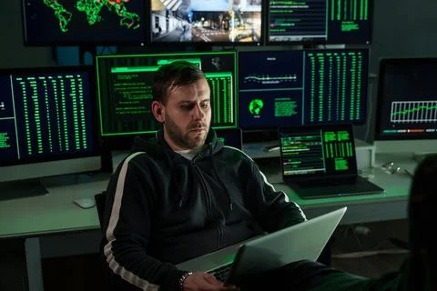 Computer hacker coding on computer while sitting at modern office full of Stock Photos