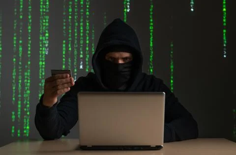 Computer hacker with credit card stealing data from a laptop concept for network Foto stock