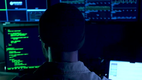 Computer hacker in front of a screen with computer code on it Stockbeeldmateriaal 282179502